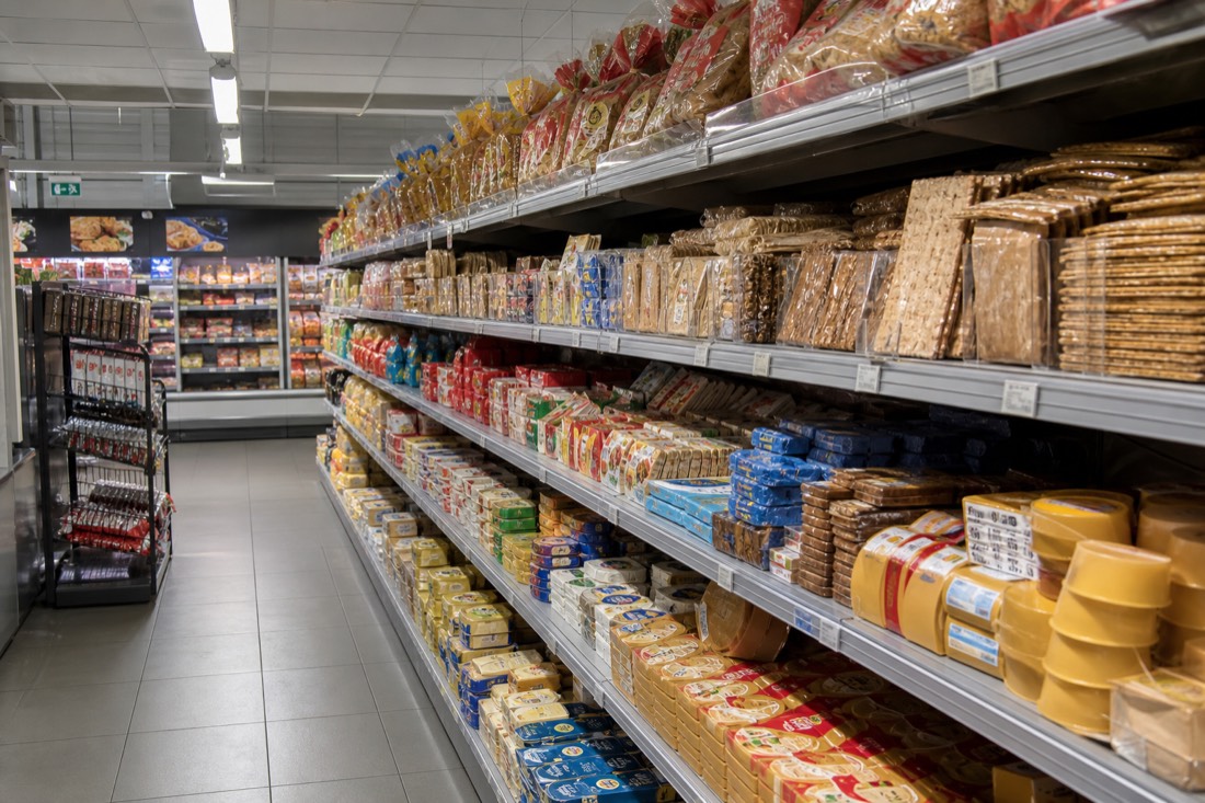 Supermarket aisle in Norway with brown cheese, dark bread and packed lunch supplies on the shelves