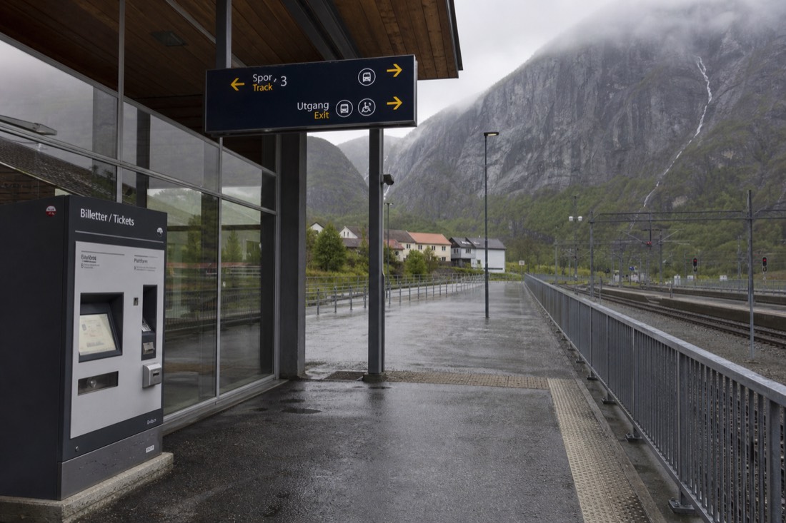 A ticket machine and station concourse in Norway with clear signage and a level walkway to the platforms
