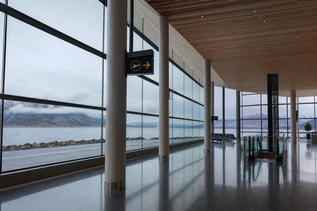 Arrivals hall at a quiet Scandinavian airport with wide windows and pale wooden ceiling panels