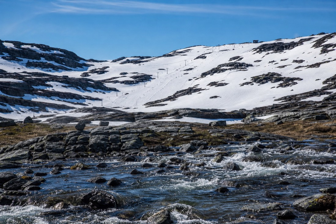 Late-season spring skiing on a sunlit Norwegian piste with bare rock showing on the ridgelines above