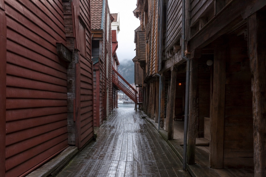Narrow wooden alleyway between leaning warehouse buildings at Bryggen with worn plank flooring